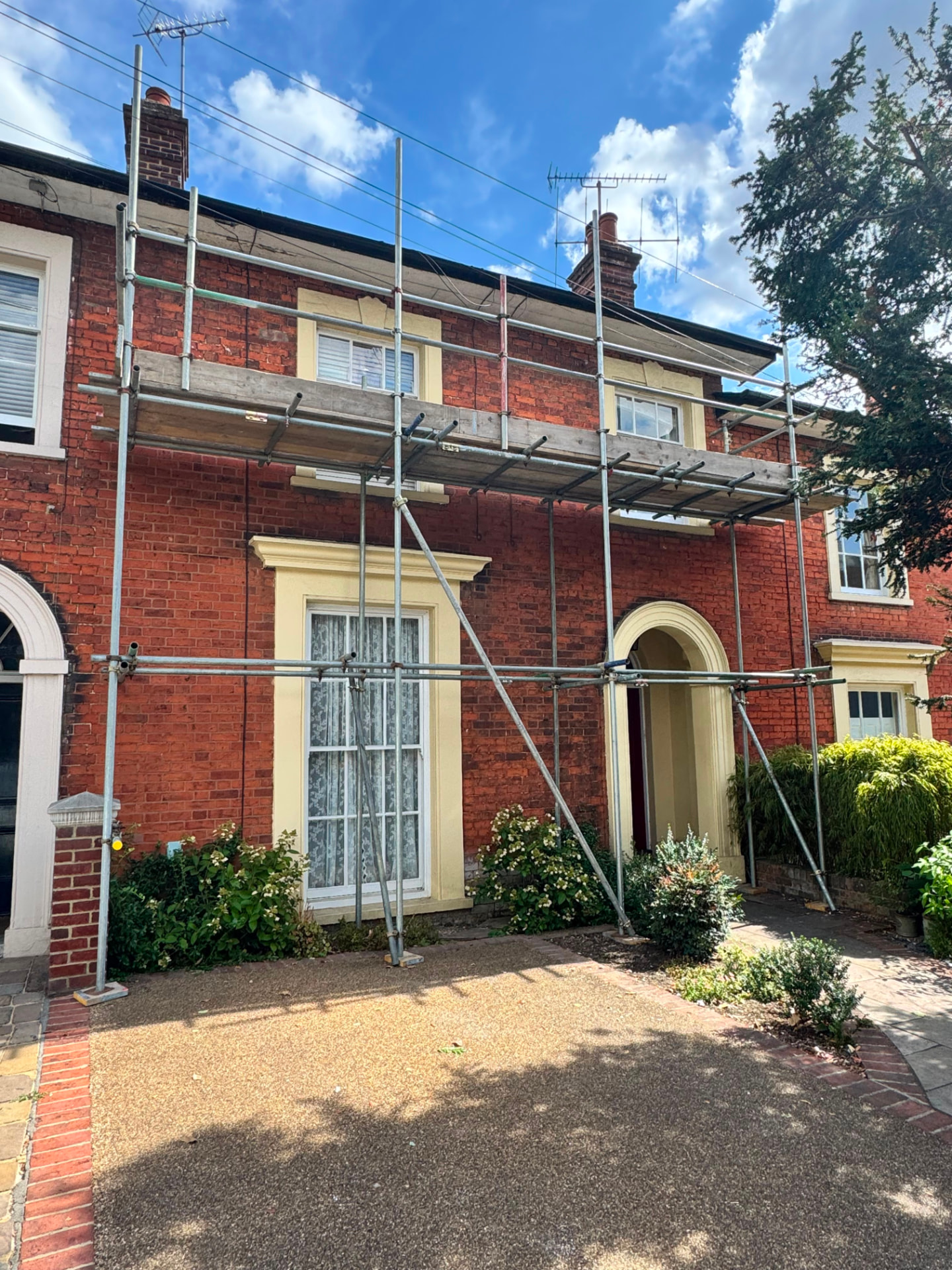 Residential scaffolding across the front elevation of a brick terraced house