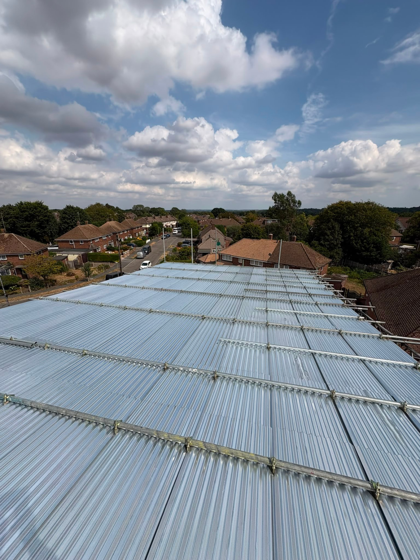 Temporary roof scaffolding with corrugated sheeting spanning a property